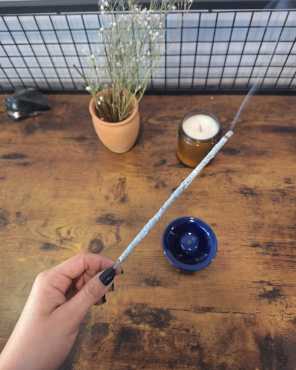 mano tomando un incienso sobre una mesa de madera